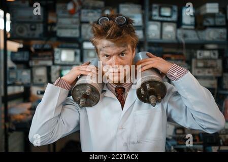 Strange scientist holds radiation devices in his hands, dangerous test in laboratory. Electrical testing tools on background. Lab equipment, engineeri Stock Photo