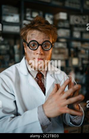 Crazy male scientist in glasses working in laboratory. Electrical testing tools on background. Lab equipment, engineering workshop Stock Photo