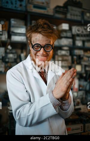 Crazy male scientist in glasses conducts a test in laboratory. Electrical testing tools on background. Lab equipment, engineering workshop Stock Photo