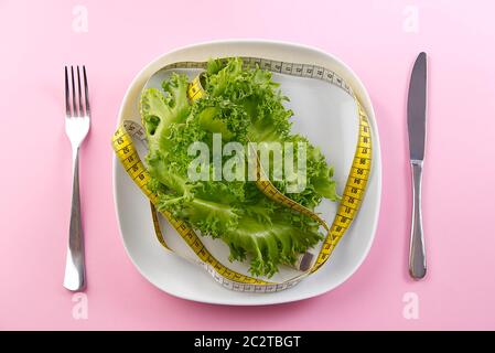 Bunch of vegetables isolated on pink background. salad tape weight. Pile of fresh vegetables salad leafe with measuring tape. Stock Photo