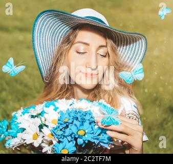 Beautiful woman with multi colored bouquet of daisies on the field background with blue butterflies close up Stock Photo