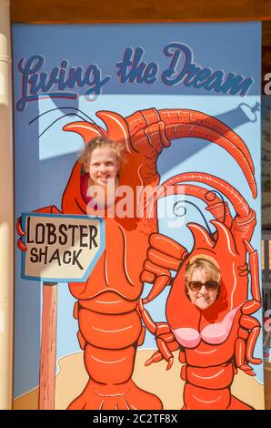 An Australian mother and young daughter smile at a photo cutout board at the Lobster Shack in the coastal fishing town of Cervantes, Western Australia Stock Photo