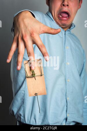 Businessman's finger catched in the mousetrap over grey Stock Photo