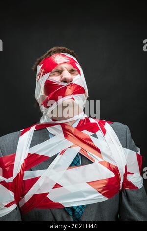 Victum man with stripped duct tape over body isolated on black Stock Photo