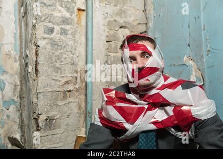 Victum man with stripped  red and white duct tape over body in old house Stock Photo