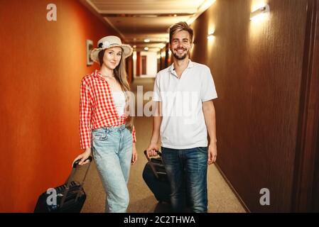 Happy couple with suitcases checking into the hotel. Travelling or tourism concept Stock Photo