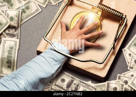 Male hand picking a gold coin catched in the mousetrap Stock Photo