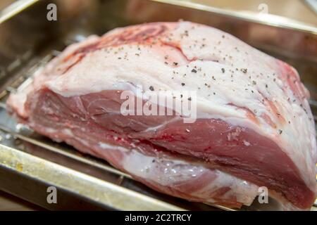 A small joint of Lamb ready on a rack in a pan to be roasted in the oven Stock Photo