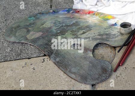 Old wooden art palette with oil paints and a brushes on the floor Stock Photo