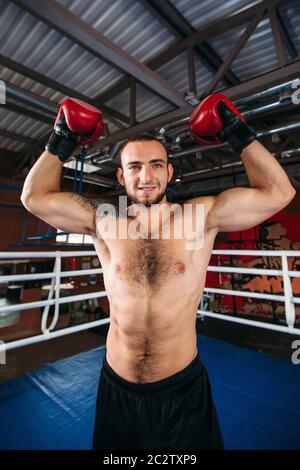 Boxer with an angry face has raised a hand up. Fighting ring on the background. Boxing power Stock Photo