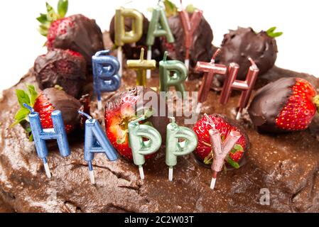 homemade chocolate cake with strawberries and happy birthday candles, close-up. Stock Photo