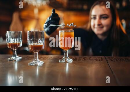 Female bartender prepares alcoholic coctail. Alcohol drink preparation. Barman working at the bar counter in pub Stock Photo