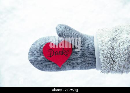 Red Heart With German Calligraphy Danke Means Thank You. Hand In A Glove With Fleece And Snow. Stock Photo