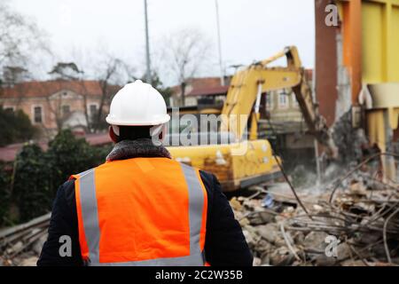 Engineer mans in helmet and jacket controlling outdoor construction ...
