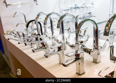 Rows of new chrome faucets in plumbing shop, closeup. Sanitary equipment Stock Photo