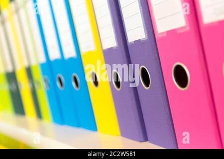 Colorful folders standing on the shelf in the office Stock Photo