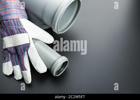 Soil-pipe and building glove on grey background Stock Photo