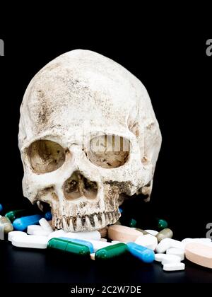 Human skull on multicolored of drug and capsule is on the black background. Close up. We are against drugs (anti drugs), cure in container for health. Stock Photo