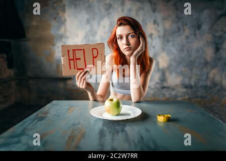 Young woman holds help sign in hand against plate with apple. Weight loss diet concept, fat burning Stock Photo