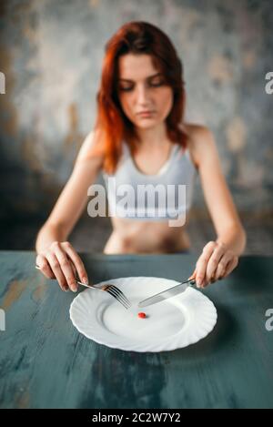 Unhappy young woman against plate with a tablet for weight loss. Fat or calories burning concept Stock Photo