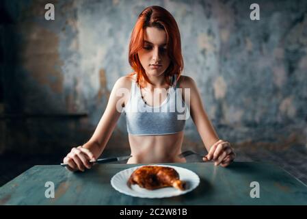 Unhappy skinny woman against plate with food, absence of appetite. Fat or calories burning concept. Weight loss, anorexia Stock Photo
