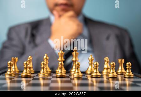 Selective focus of golden chess in front of professional business analysis man. Concept of leadership must-have solution for the financial crisis Stock Photo