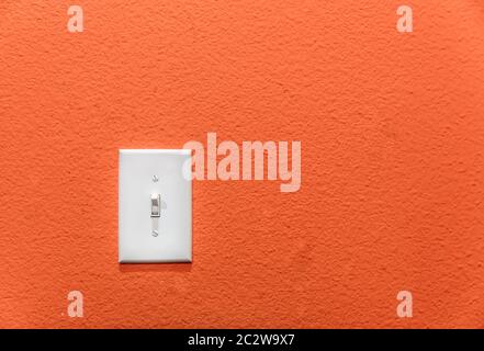 White power switch, turn on or turn off the power on orange wall. Stock Photo