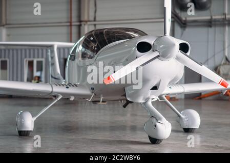 Small private turbo-propeller airplane in hangar, plane on inspection before flight. Air transportation, front view on turboprop plane Stock Photo