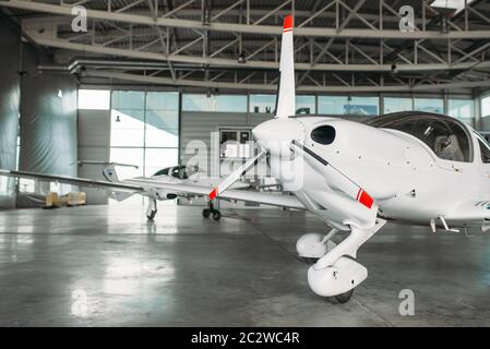 Small private turbo-propeller airplane in hangar, plane on inspection before flight. Air transportation, front view on turboprop plane Stock Photo