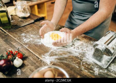 Homemade pasta cooking, bearded chef preparing dough on wooden kitchen table Stock Photo