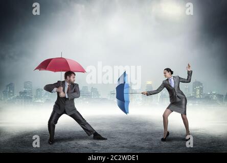 Business people fighting with umbrellas against cityscape in the night Stock Photo