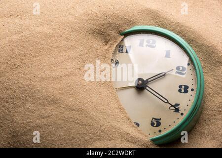 Old alarm clock in sand Stock Photo