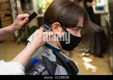 Guy in a black protective mask is cut in a beauty salon Stock Photo