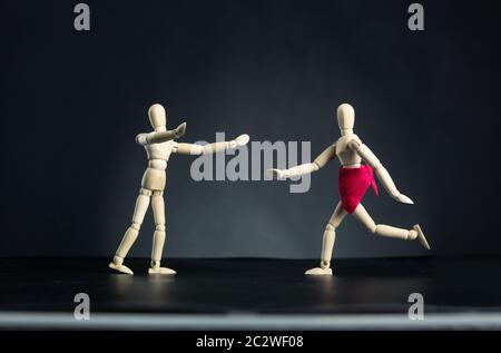 Wooden carved figures, woman running to man over black Stock Photo
