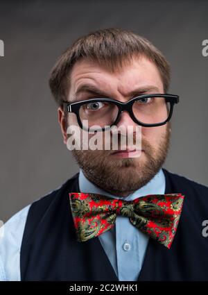 Strange suspicious-looking nerd in glasses looks at you over grey background Stock Photo
