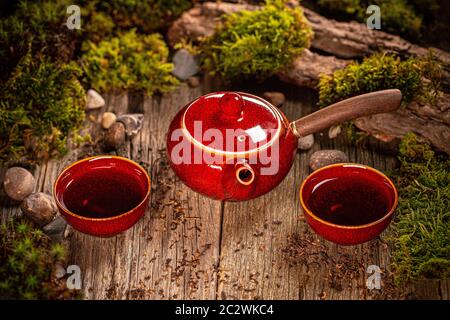 Tea time concept. Red ceramic teapot and cups, against wooden background. Stock Photo