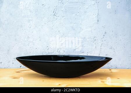 black oval bowl on wooden table with grey background Stock Photo