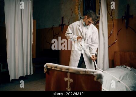 Psychiatrist ties to bed crazy female patient, mental hospital. Woman undergoing treatment in clinic for the mentally ill Stock Photo