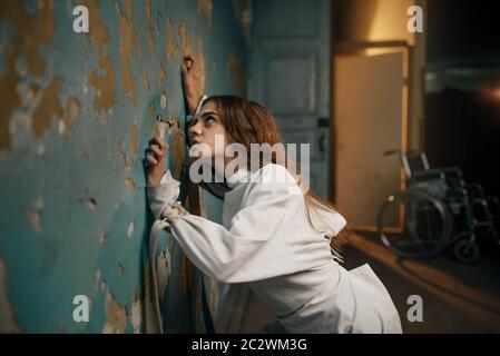 Female patient in straitjacket, mental hospital. Woman in strait jacket undergoing treatment in clinic for the mentally ill, insanity Stock Photo