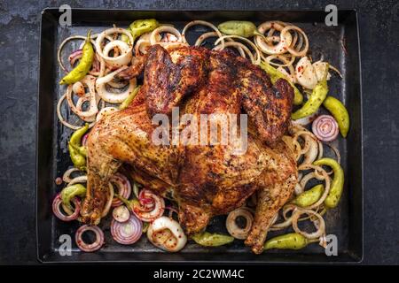 Barbecue spatchcocked barbecue chicken al mattone chili with peperoni and onions as top view on an old metal sheet Stock Photo