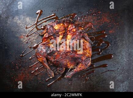 Barbecue spatchcocked barbecue chicken al mattone with hot chili sauce as top view on an old metal sheet Stock Photo