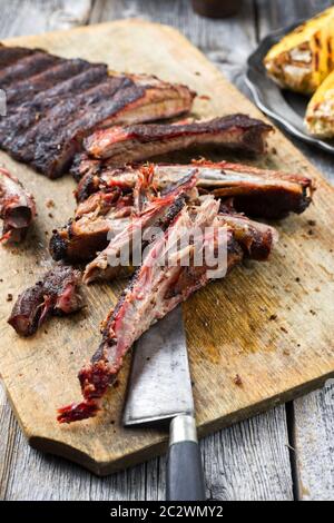 Barbecue spare ribs St Louis cut with hot rub and corn as closeup on a wooden cutting board Stock Photo