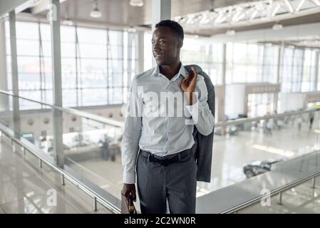 Happy black businessman with briefcase in car dealership. Successful business person on motor show, black man in formal wear, automobile showroom Stock Photo