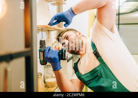 Repairman in uniform holds screwdriver, handyman. Professional worker makes repairs around the house, home repairing service Stock Photo