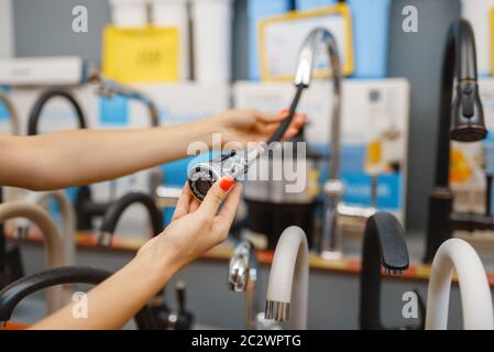 Female customer choosing water tap in hardware store. Woman in diy shop, shopping in building supermarket, sanitary engineering department Stock Photo