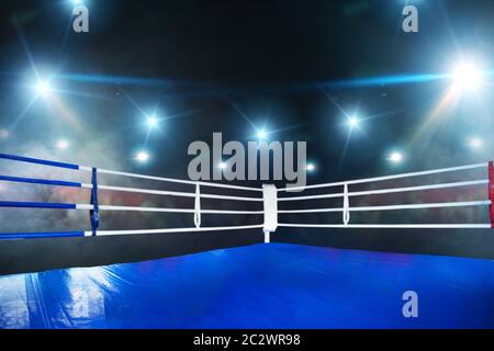 Empty boxing ring, blue flooring, view on corner with white ropes. Professional arena for sport competitions and fighting tournaments, nobody, bright Stock Photo