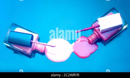 Spilled nail polish bottles on a blue background Stock Photo