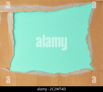 torn edges of corrugated brown cardboard paper on a green background. Ripped paper texture Stock Photo