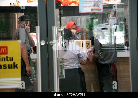 Mc Donalds employees wear mask and face shield on the ground floor specifically for Gambir Station food stores, Jakarta. To safeguard the safety and security of consumers and employees, McDonald's (McD) increases precautions to ensure its outlets are clean and safe, at a new period of normal enforcement amid the ever-increasing number of COVID-19 positive cases. Actions taken such as checking body temperature for all McD employees and suppliers every day before work. And also enforces a one-door policy in restaurants and checks the body temperature of all consumers who will enter the restauran Stock Photo