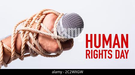 Hand holding microphone and have roped on fist hand with HUMAN RIGHTS DAY text on white background, Human rights day concept Stock Photo